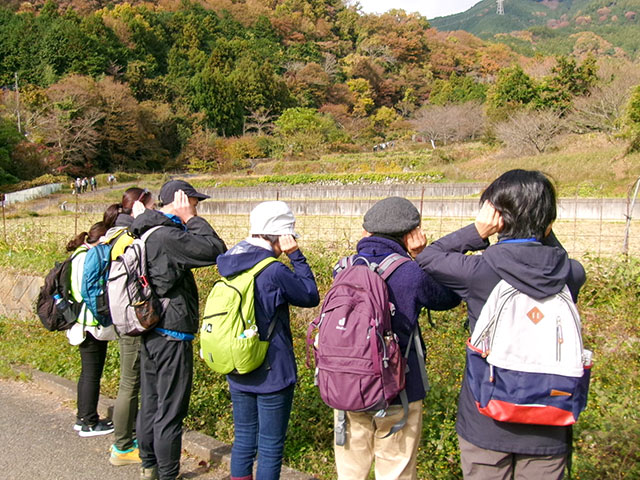 小川に流れる水の音に耳を澄ませる参加者6人